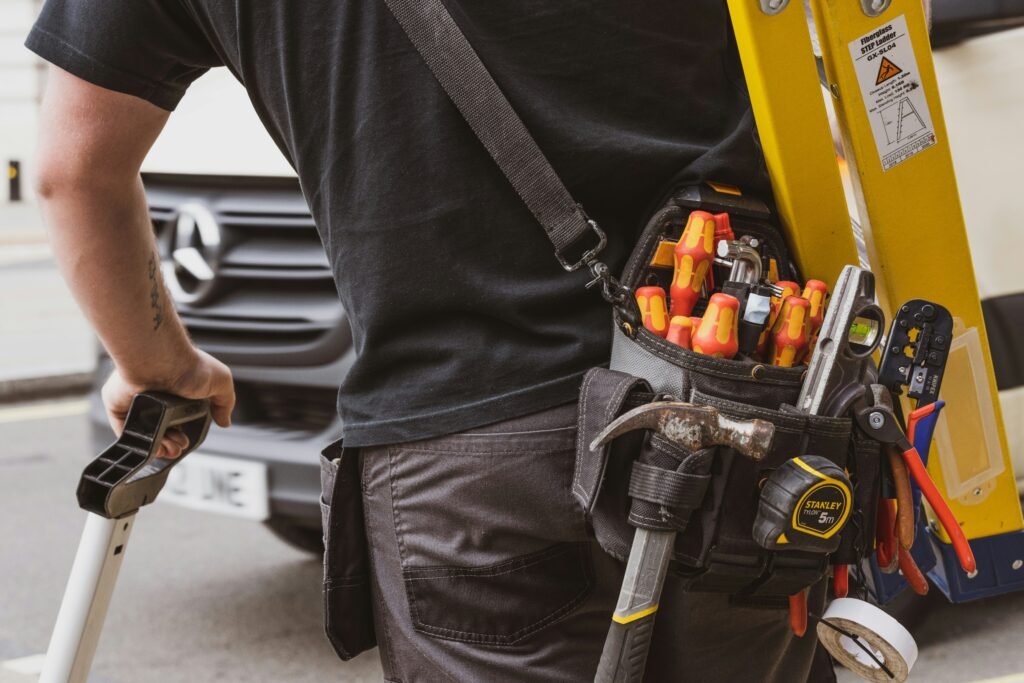 Tradesperson carrying a ladder and tool belt beside a work van – Local Services Ads